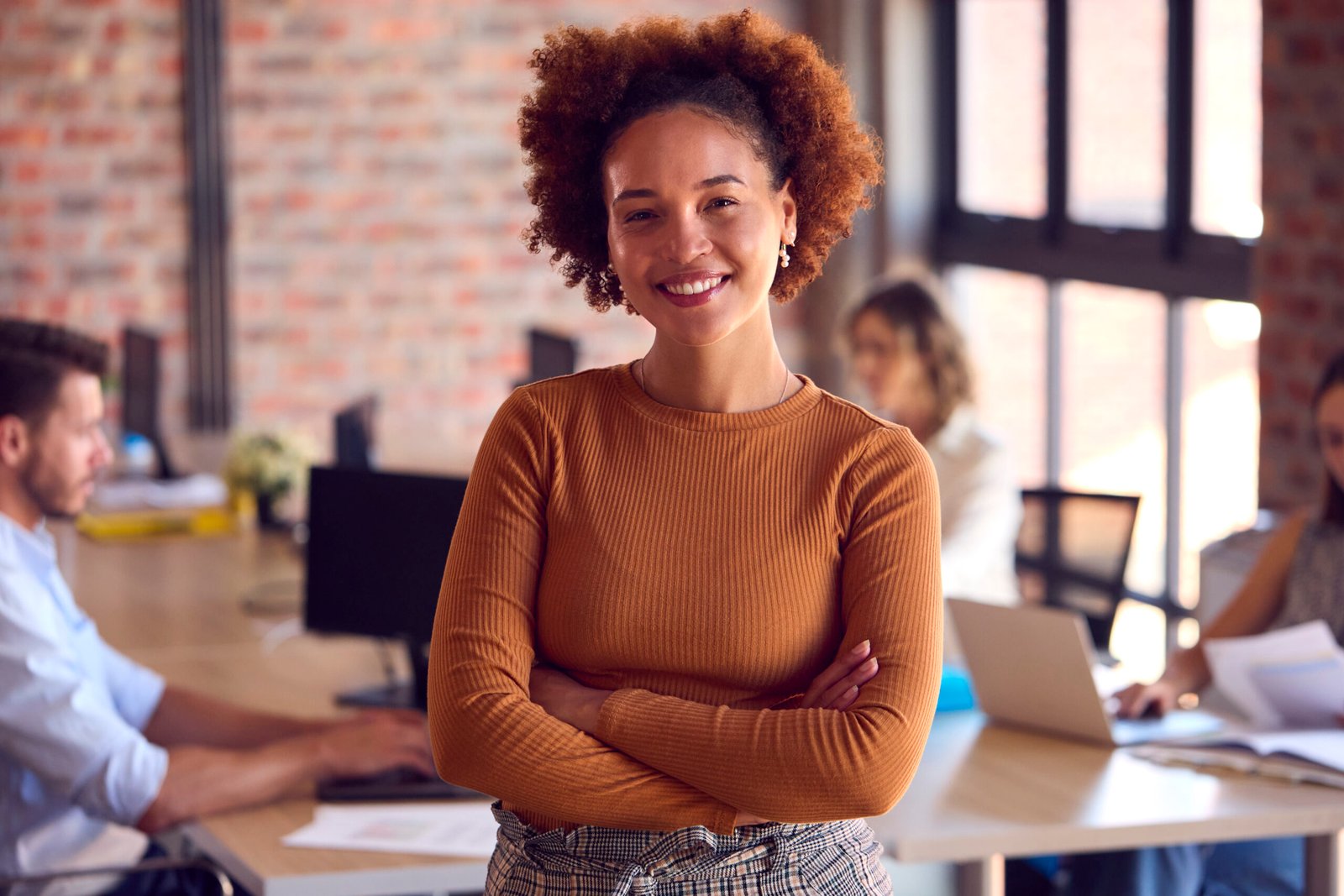 Portrait Of Smiling Businesswoman Standing In Busy Office