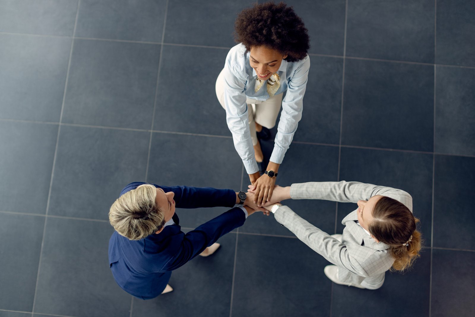 Above view of female business team holding hands in unity.